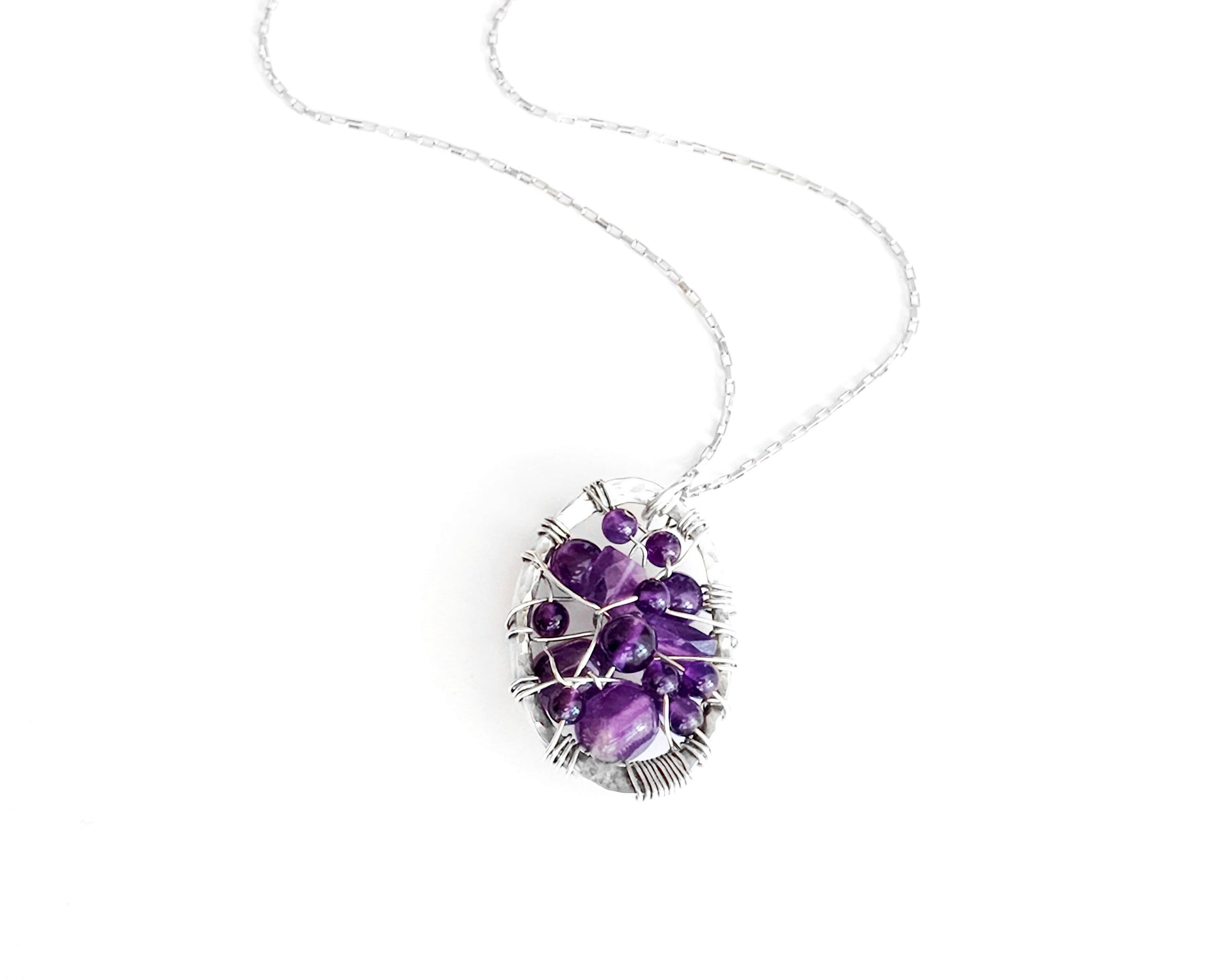 Oval shaped Sterling Silver Amethyst pendant woven with purple gemstones and Sterling Silver wire, pendant on chain.