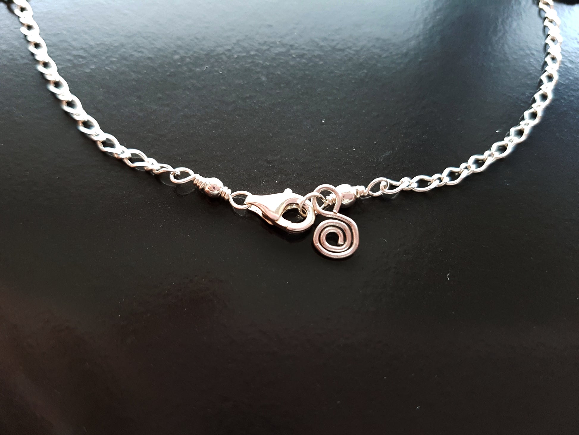 Anklet end with lobster claw clasp and Celtic Eternity Coil dangling on the end.