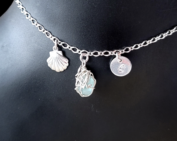 Silver Anklet with Fancy Chain and dangling Shell, Aqua Blue Beach Glass wire wrapped pendant and round disk shaped initial pendant on black background 