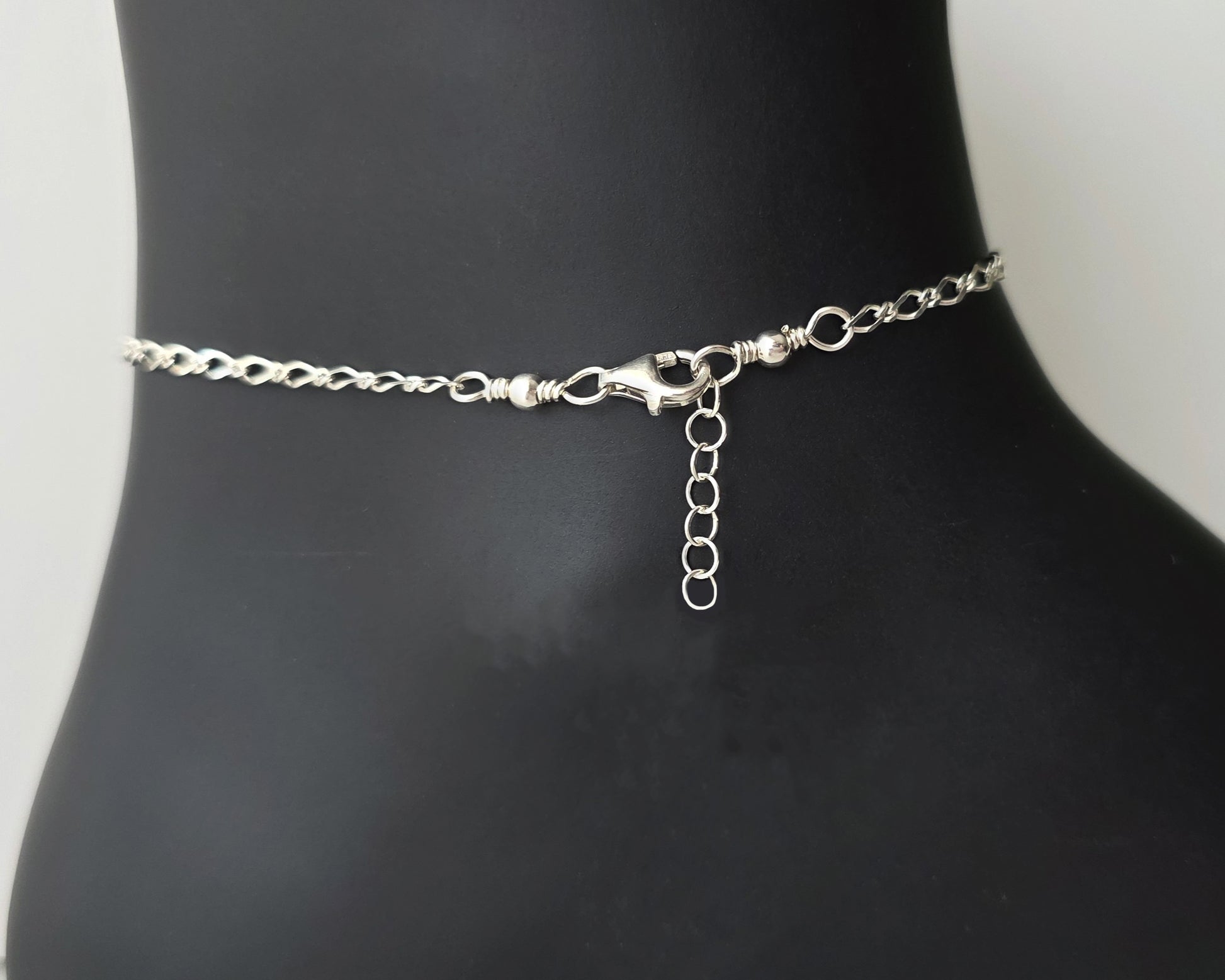 Lobster Claw Clasp, Eternity Coil pendant, flat figaro chain on black background 