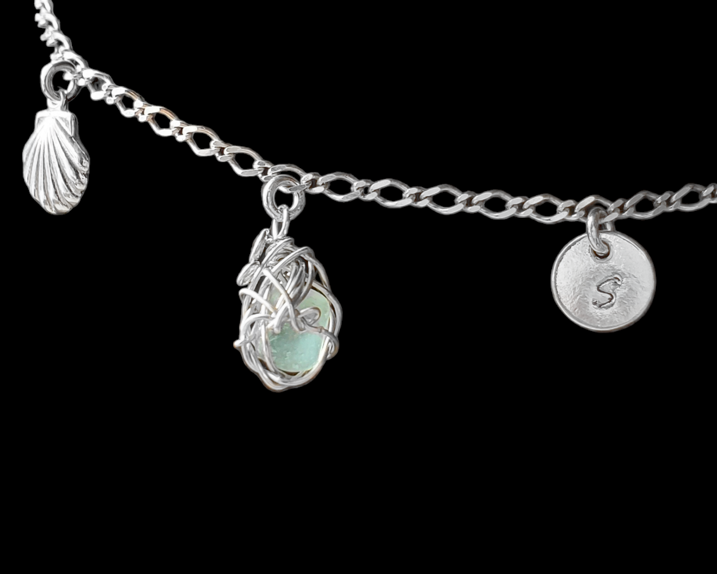 Sterling Silver Aqua Blue Beach Glass/ Sea Glass Anklet, Ankle Bracelet with a Shell, round Initial pendant and Celtic Eternity Coil pendant on flat figaro chain on black background 