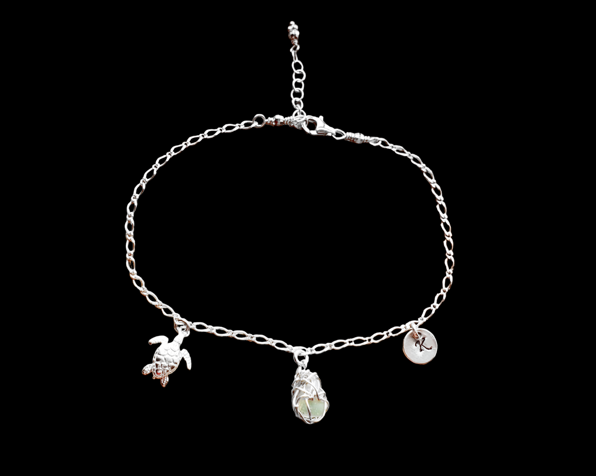 Sterling Silver Aqua Blue Beach Glass/ Sea Glass Anklet, Ankle Bracelet with a Turtle, round Initial pendant and Celtic Eternity Coil pendant on flat figaro chain on black background 