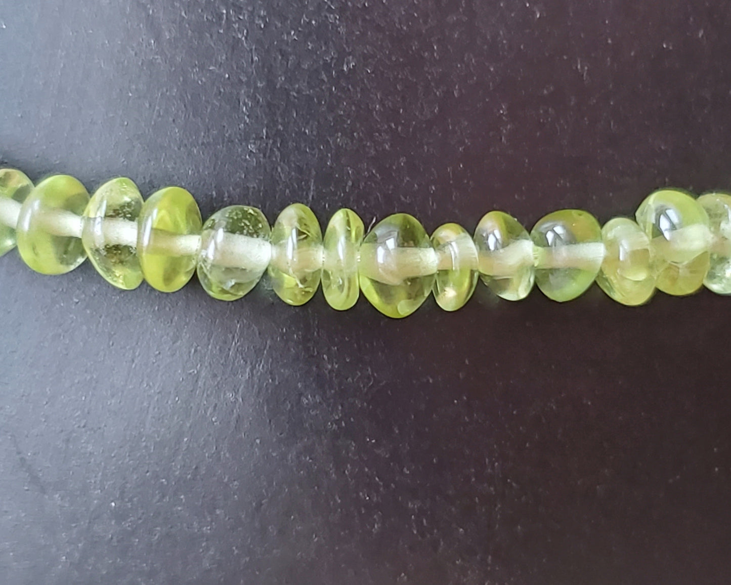 small beaded green peridot gemstones on Black display