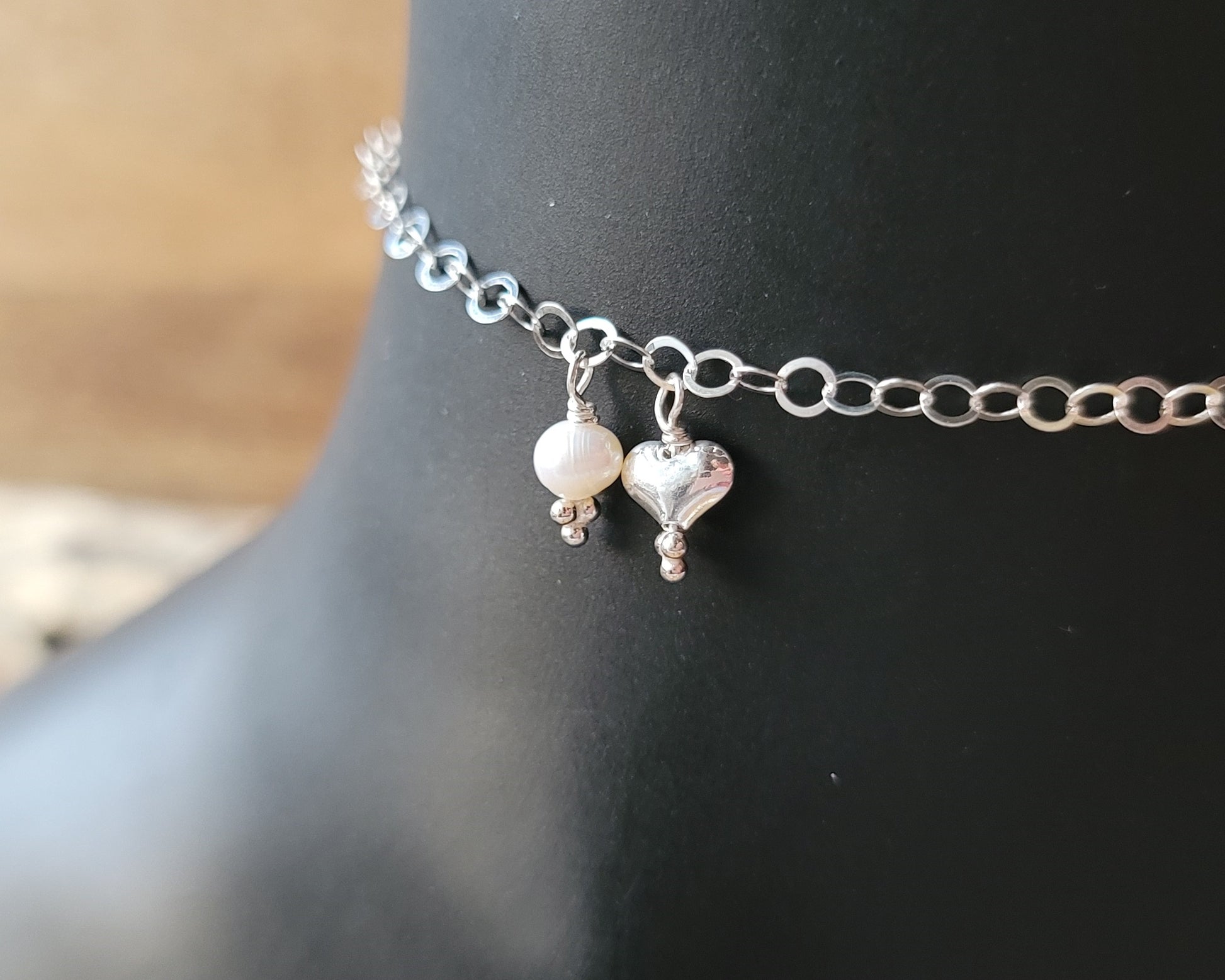 Silver Chain Anklet Ankle Bracelet with a small dangling heart and pearl on black foot