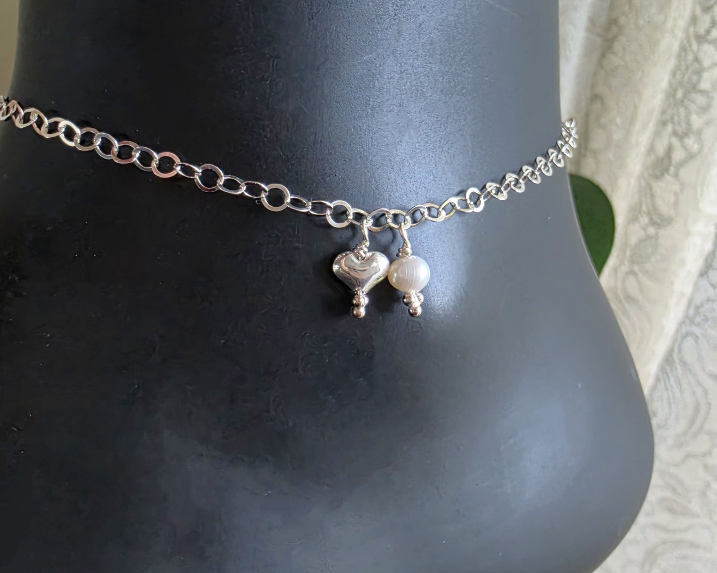 Silver Chain Anklet Ankle Bracelet with a small dangling heart and pearl on black foot