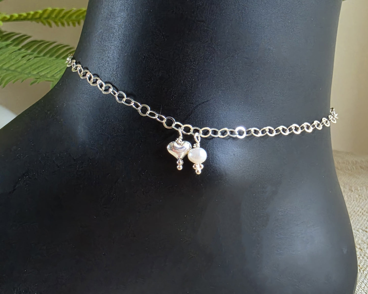 Silver Chain Anklet Ankle Bracelet with a small dangling heart and pearl on black foot