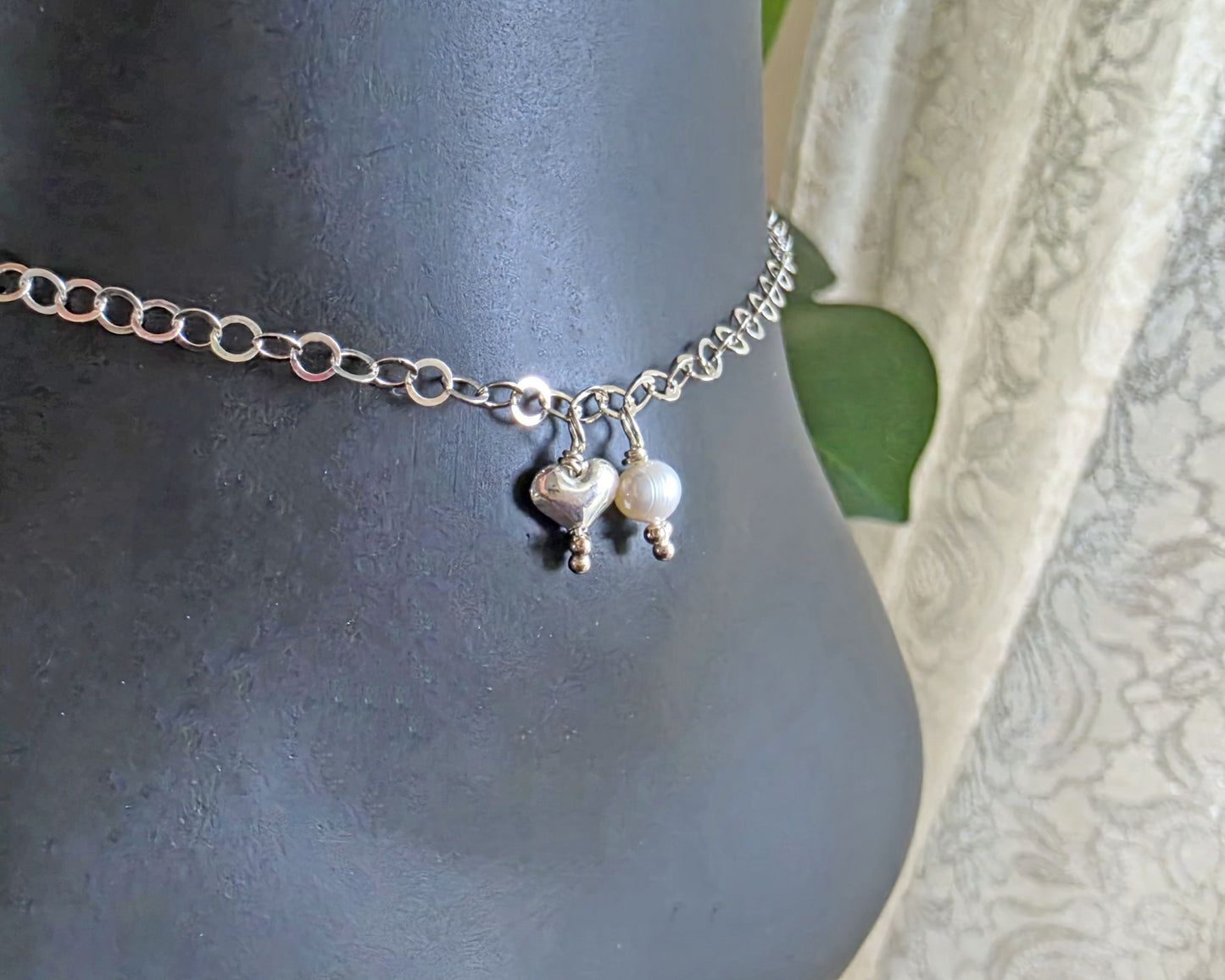 Silver Chain Anklet Ankle Bracelet with a small dangling heart and pearl on black foot