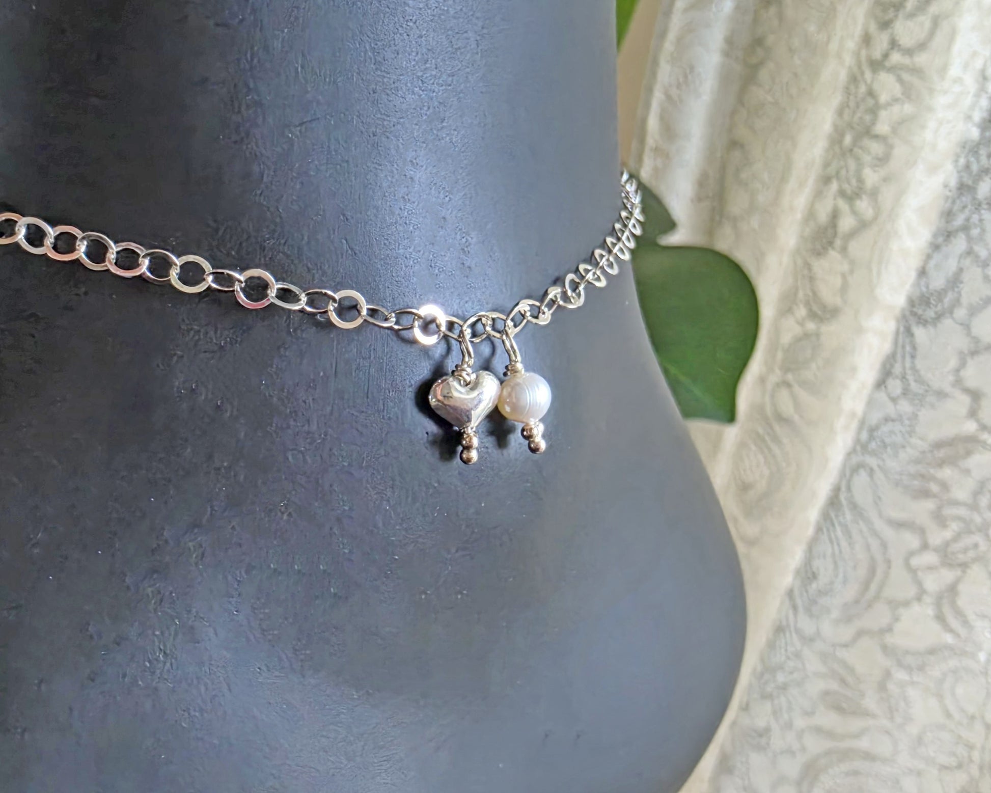 Silver Chain Anklet Ankle Bracelet with a small dangling heart and pearl on black foot
