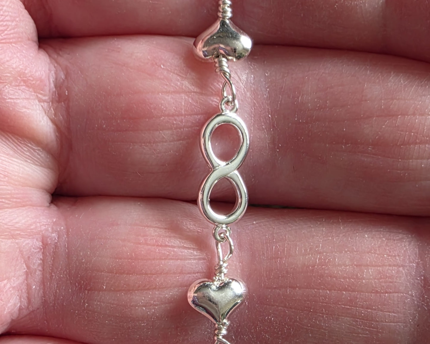 Silver Chain Anklet Ankle Bracelet with a small dangling heart and pearl on black foot