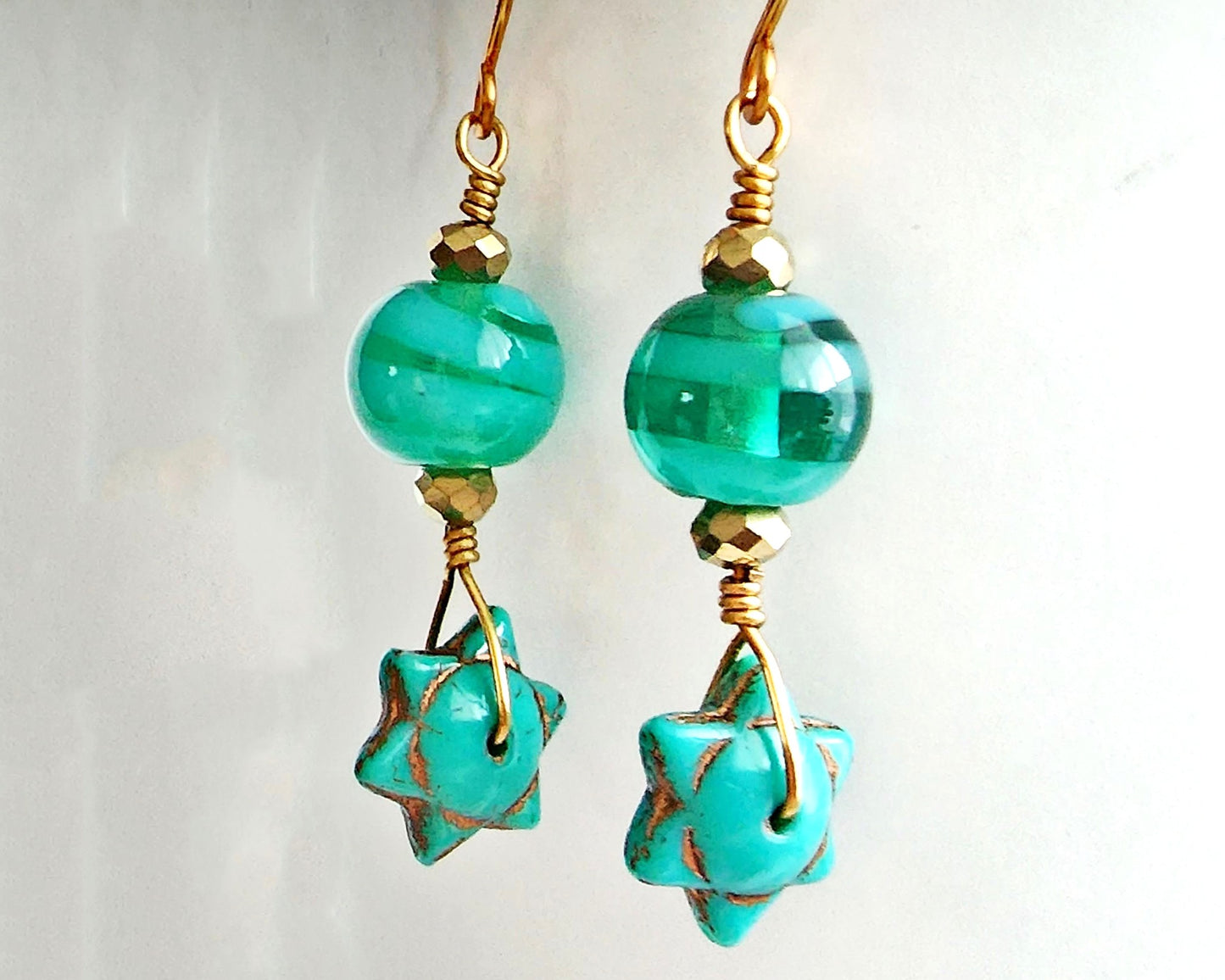 Handmade Turquoise Star beaded Wire Wrapped long dangle earring with gold wire and sparkly gold beads on french hooks with white background 