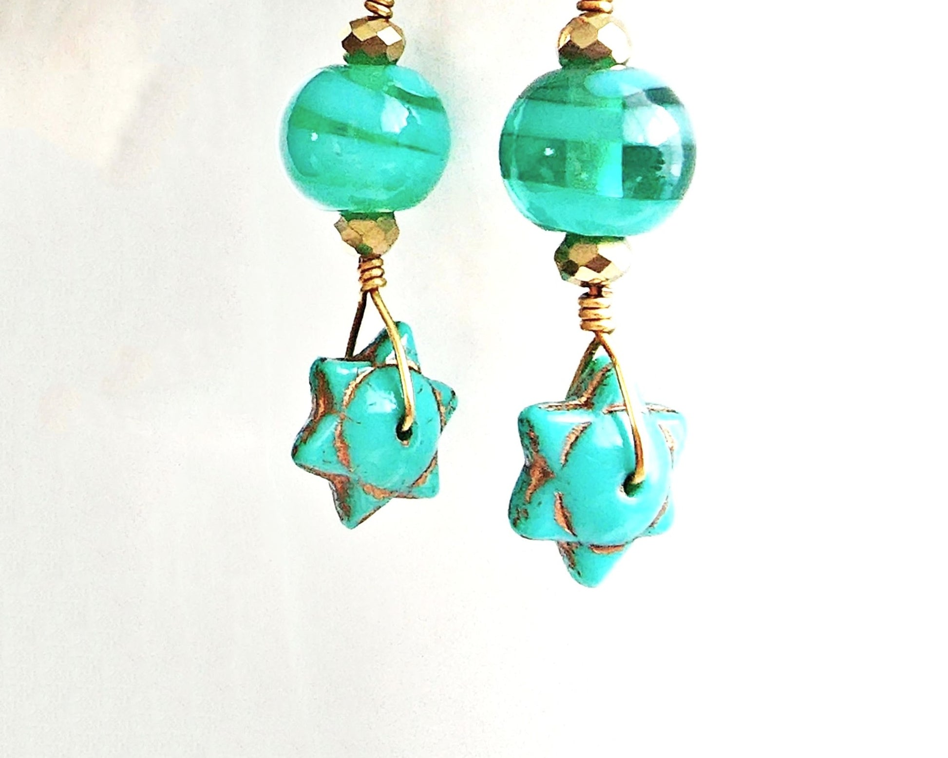 Handmade Turquoise Star beaded Wire Wrapped long dangle earring with gold wire and sparkly gold beads on french hooks with white background 