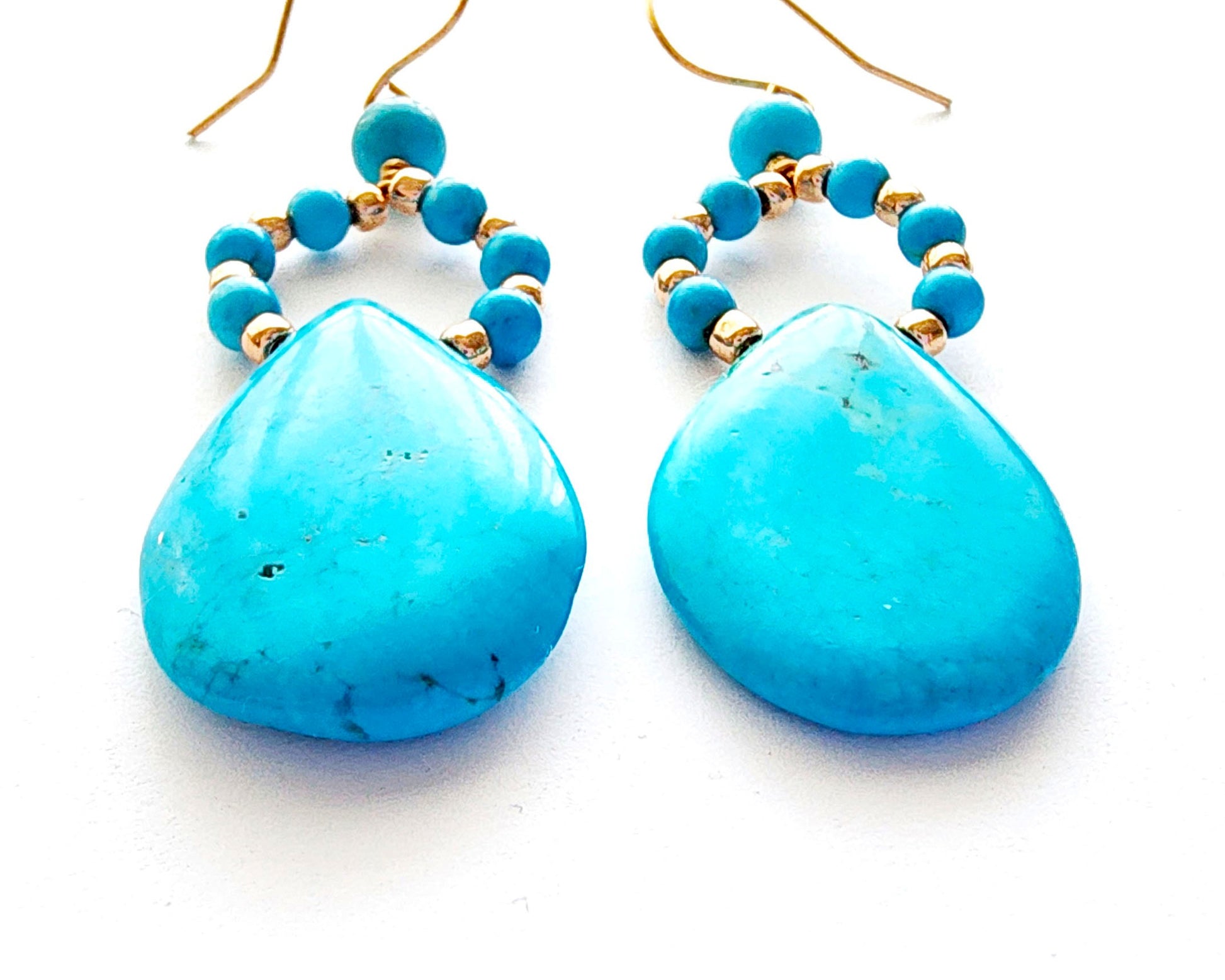 Long turquoise blue drop shape hoop dangle earring with large drop shape stones and gold wire and french earring hooks on white background
