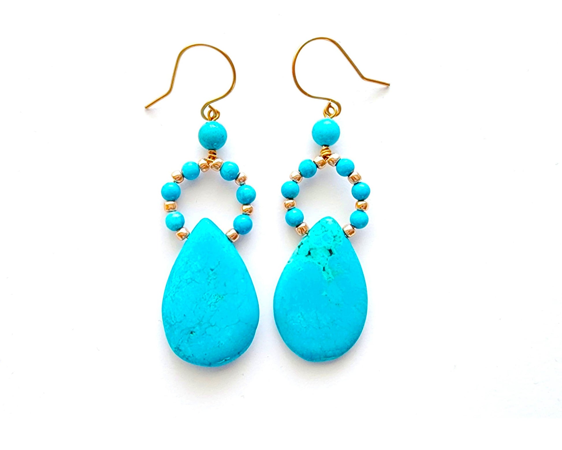 Long turquoise blue drop shape hoop dangle earring with large drop shape stones and gold wire and french earring hooks on white background