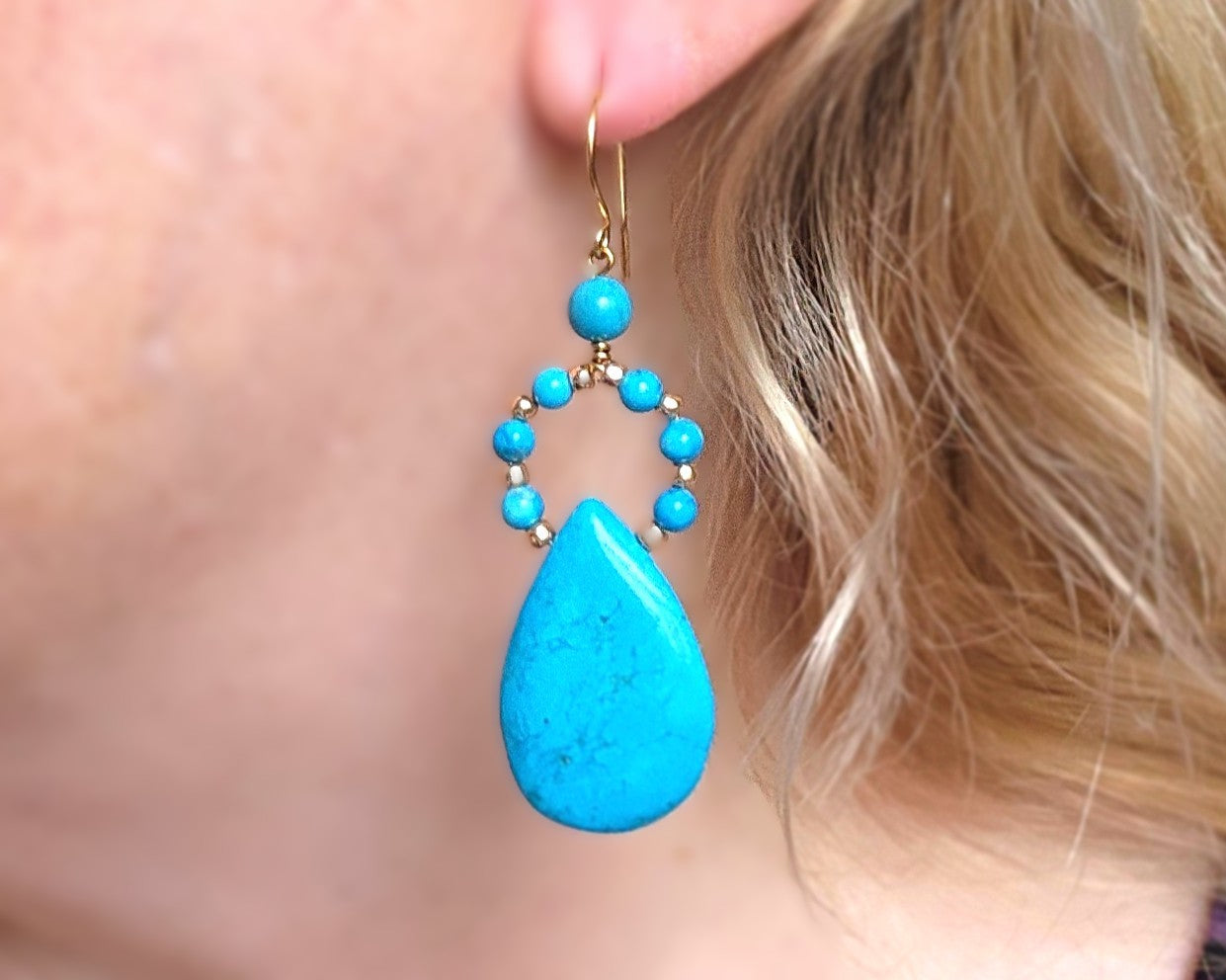 Close up of  Long turquoise blue drop shape hoop dangle earrings on an ear 