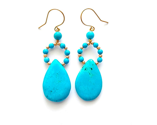 Long turquoise blue drop shape hoop dangle earring with large drop shape stones and gold wire and french earring hooks on white background