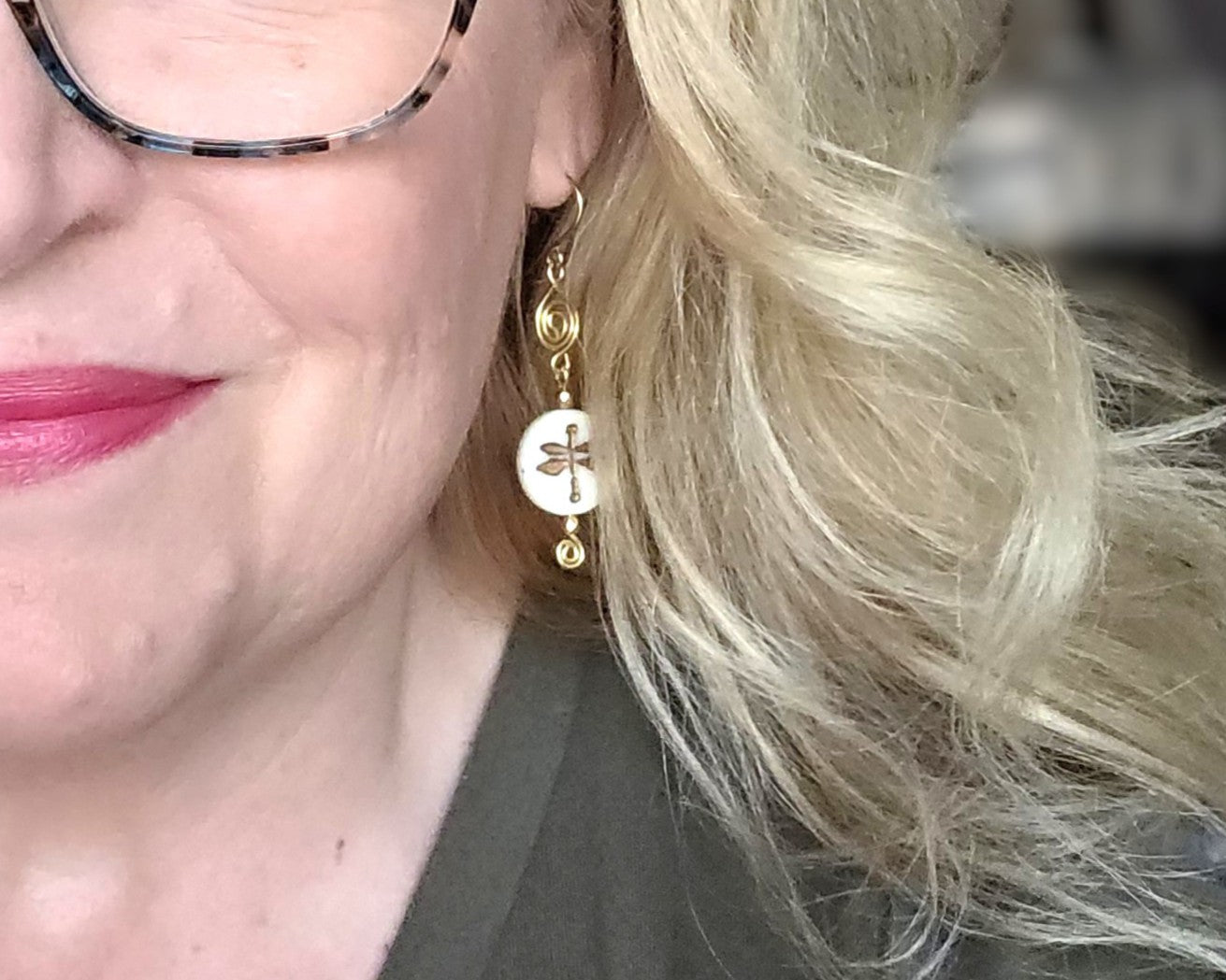 Gold and white dragonfly earrings with Celtic Coils and french style earring hooks worn by a person with blonde hair.
