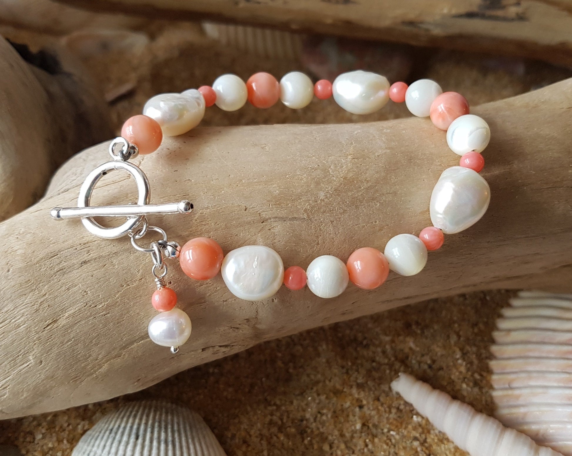 Angle Skin Coral, Mother of Pearl, Freshwater Cultured Pearl Beaded Bracelet. Pale orange Coral, white Mother of Pearl, white Pearls. Round Toggle clasp. Sterling Silver