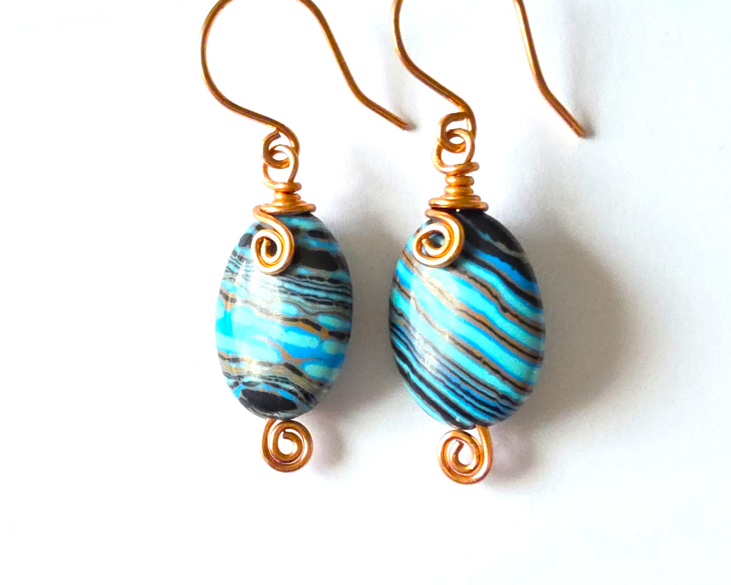 Celtic style marbled multi color copper earrings with coils and french earring hooks with white background 