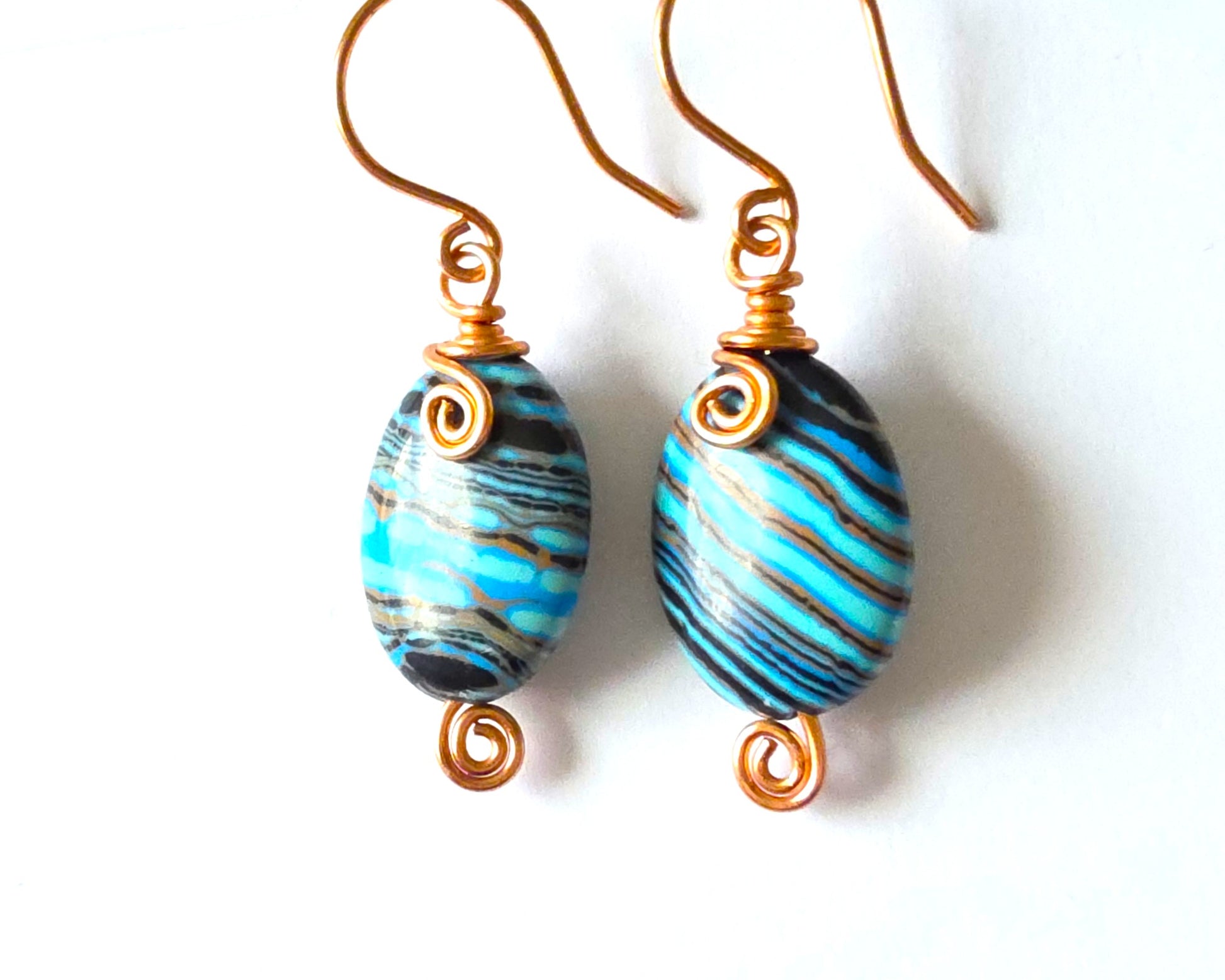 Celtic style marbled multi color copper earrings with coils and french earring hooks with white background 