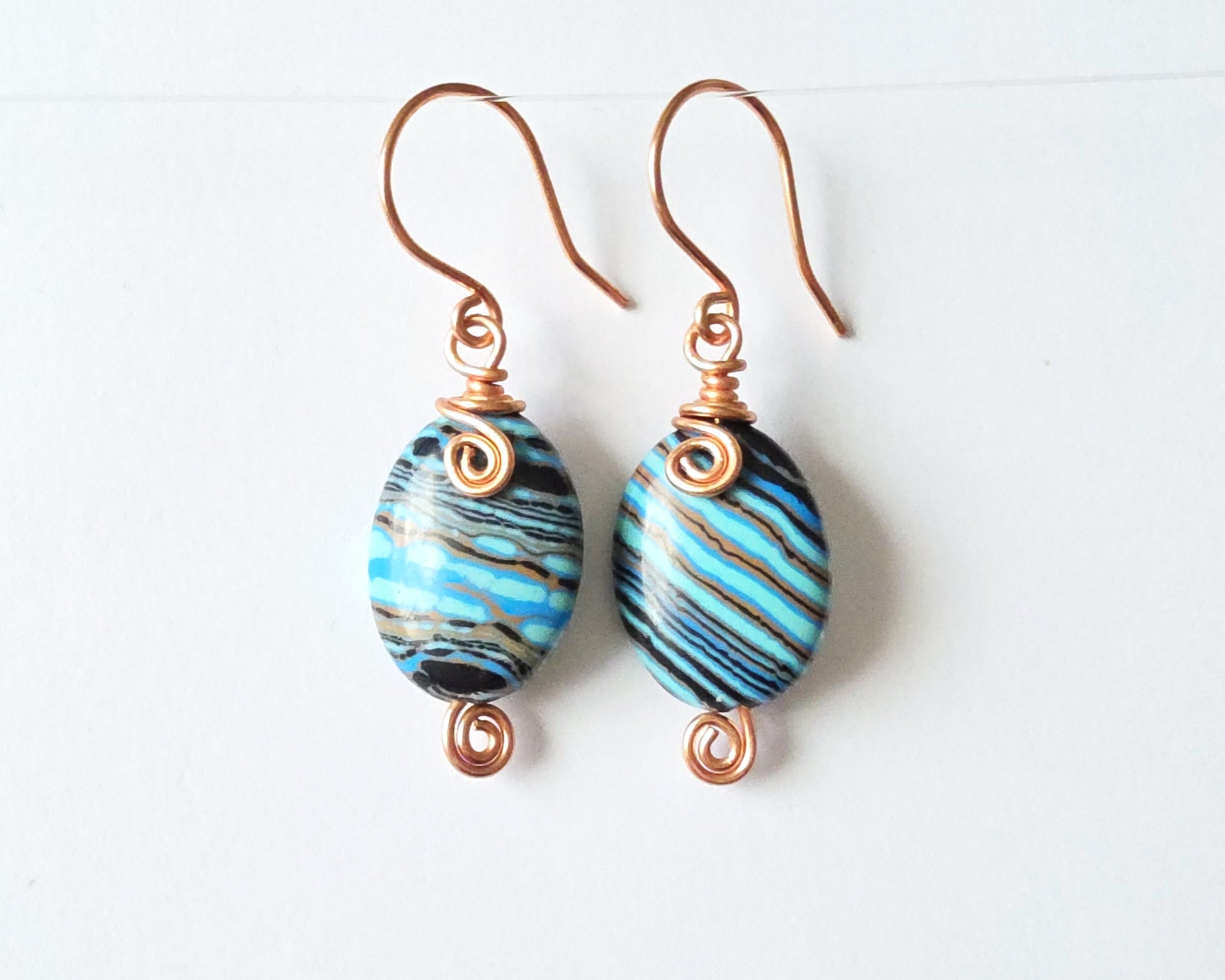 Celtic style marbled multi color copper earrings with coils and french earring hooks with white background 