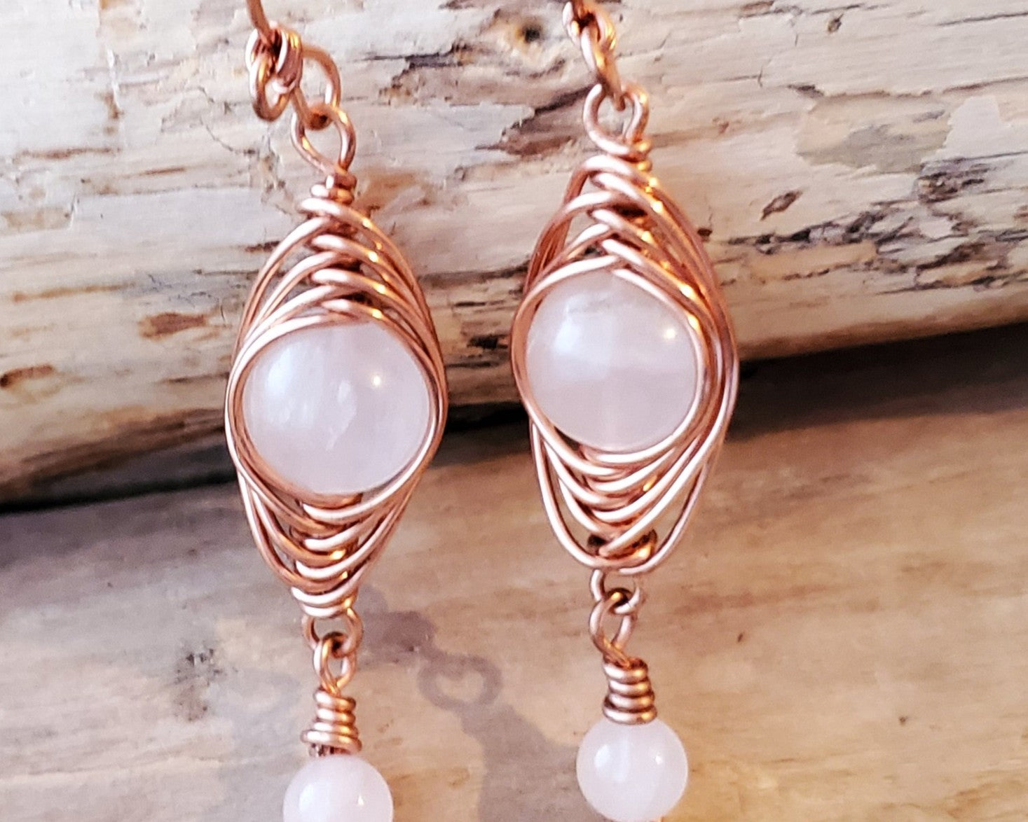 Long Copper Earrings with Pink Stones with wood background 
