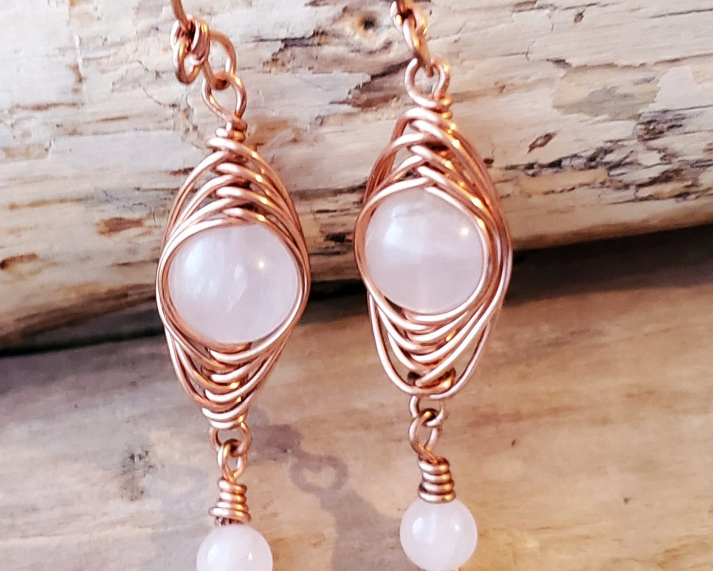 Long Copper Earrings with Pink Stones with wood background 
