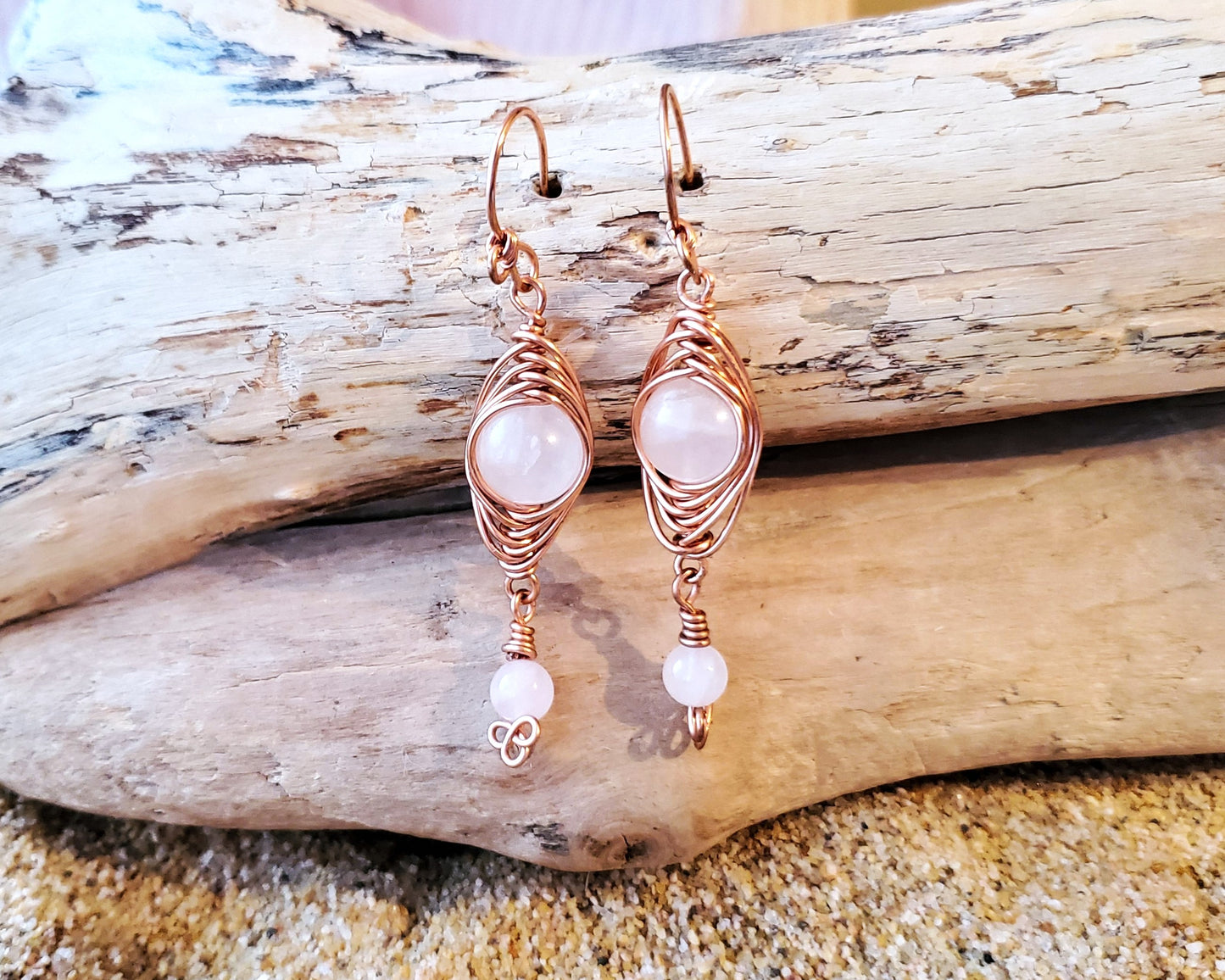 Long Copper Earrings with Pink Stones with wood background 
