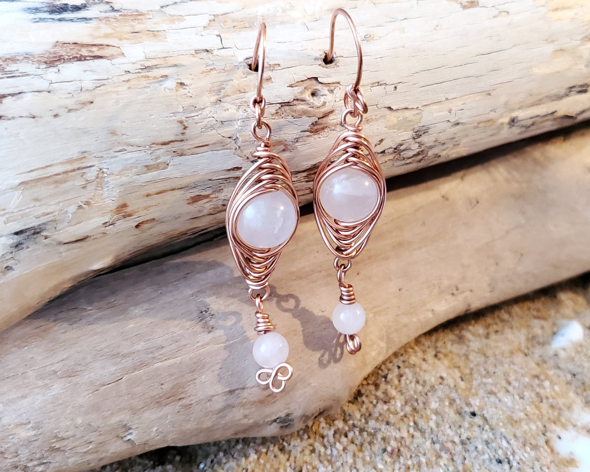 Long Copper Earrings with Pink Stones with wood background 
