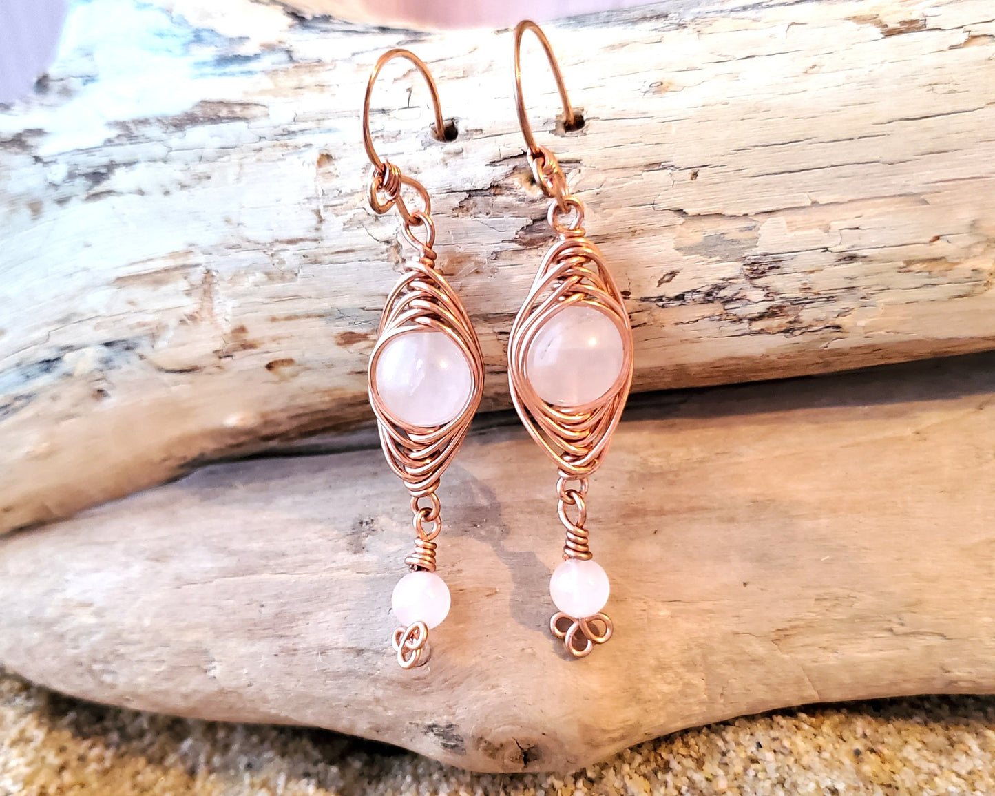 Long Copper Earrings with Pink Stones with wood background 
