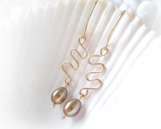 Long Gold Swirling, Wavy Design Earrings and drop shape gold Freshwater Cultured Pearls dangling from French style earring hooks, on white Background  