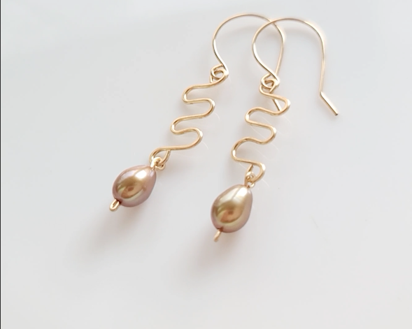 Long Gold Swirling, Wavy Design Earrings and drop shape gold Freshwater Cultured Pearls dangling from French style earring hooks, on white Background  