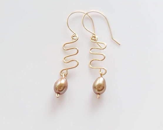Long Gold Swirling, Wavy Design Earrings and drop shape gold Freshwater Cultured Pearls dangling from French style earring hooks, on white Background  
