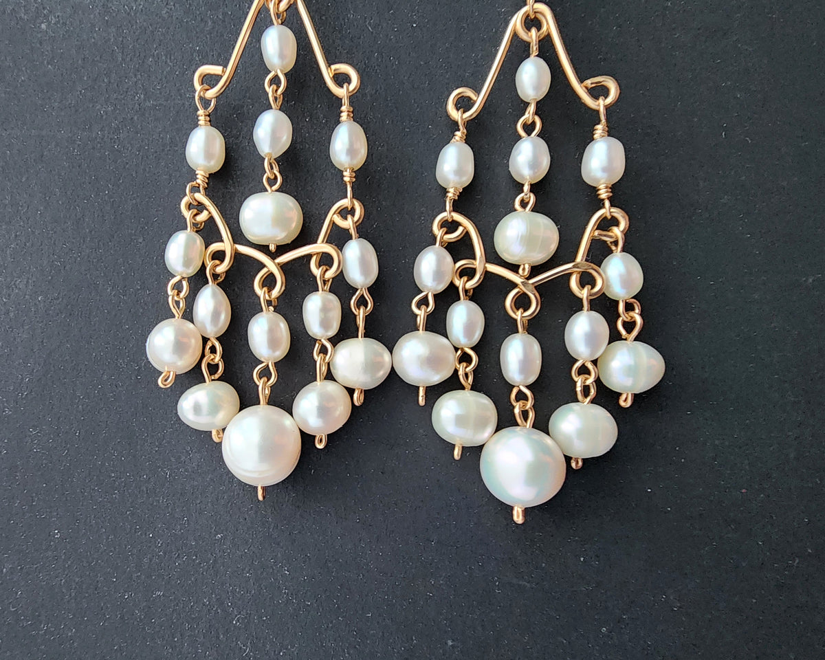 A pair of Long bohemian style elaborate pearl chandelier earrings, 14k Gold Filled and white Freshwater Cultured Pearls on dark gray background 
