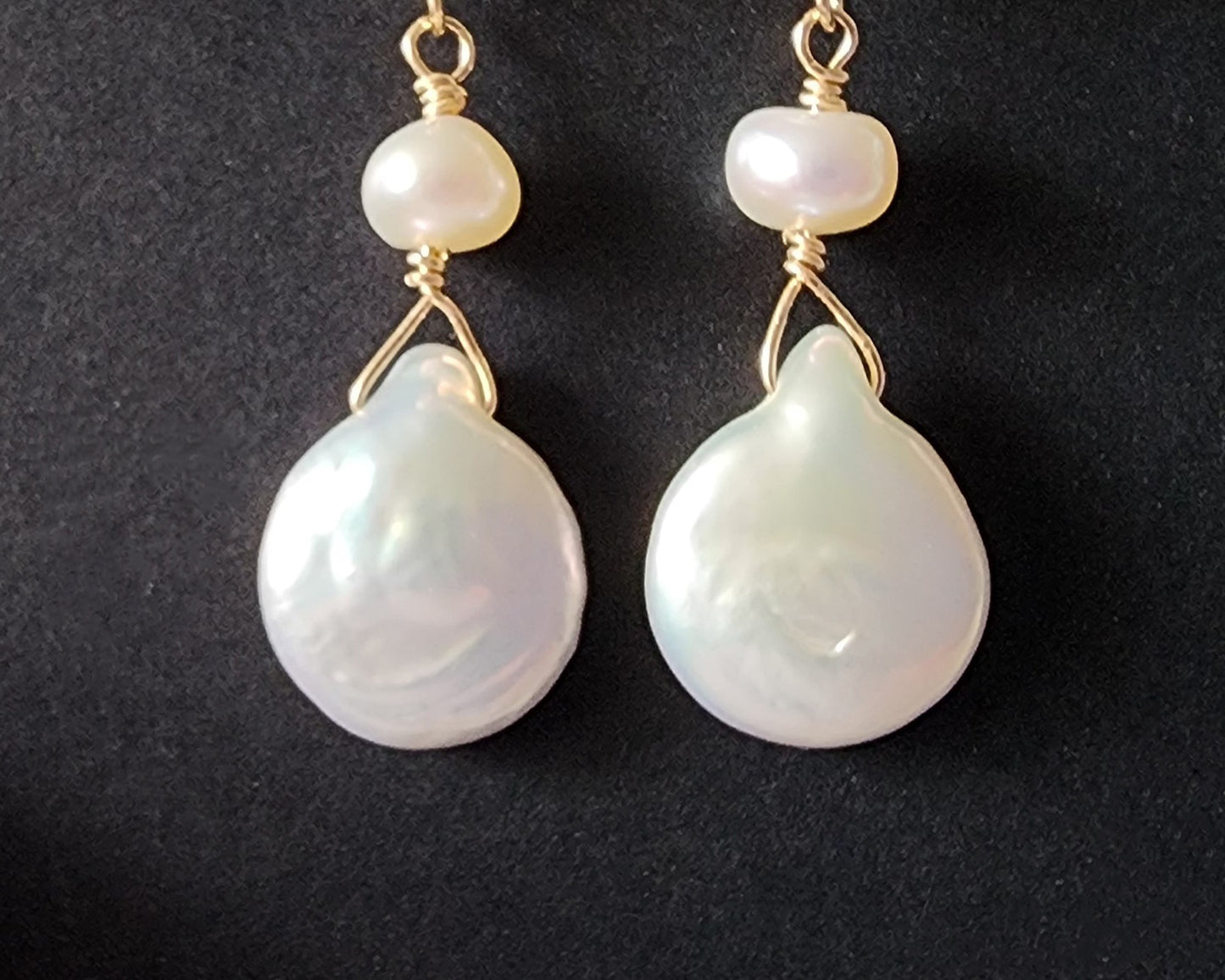 A pair of long handmade Art Deco style white pearl  gold dangle earrings,  French earrings hooks on black background 