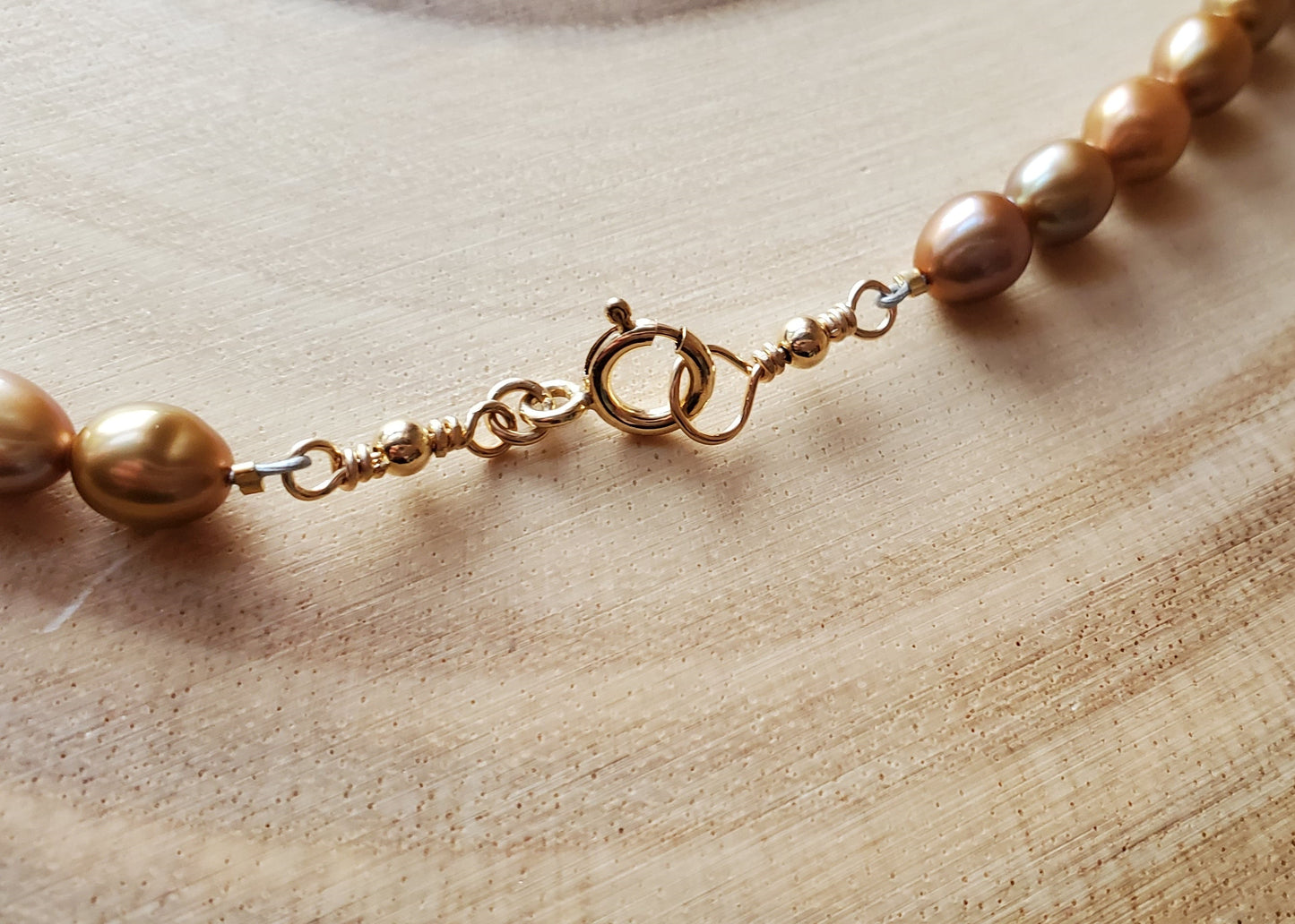 14k Gold Filled clasp, wire wrapped beaded loops and gold pearls on wood.