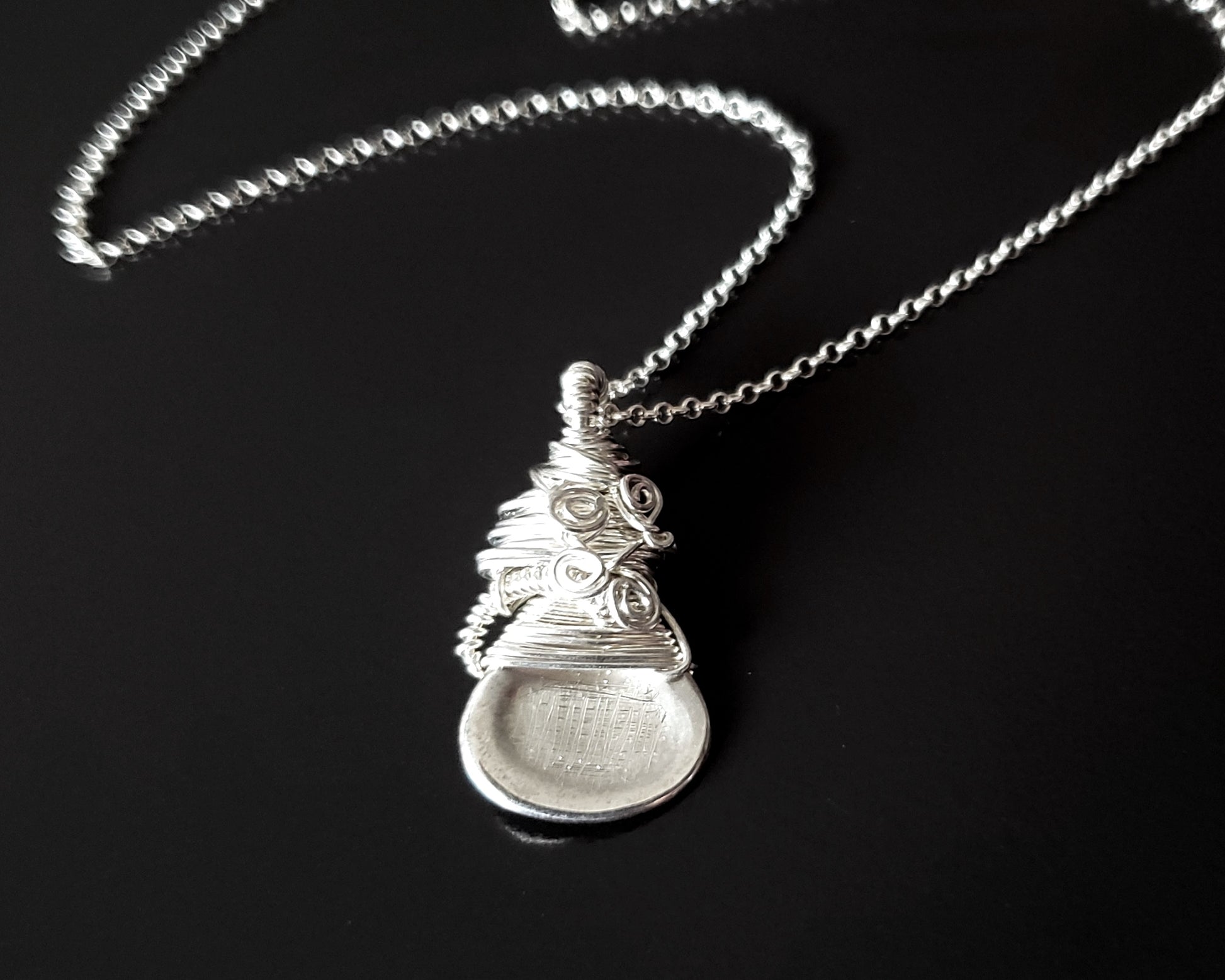 Sterling Silver Sculptural and Wire Wrapped Pendant with coils and texture on a rolo style chain on black background 