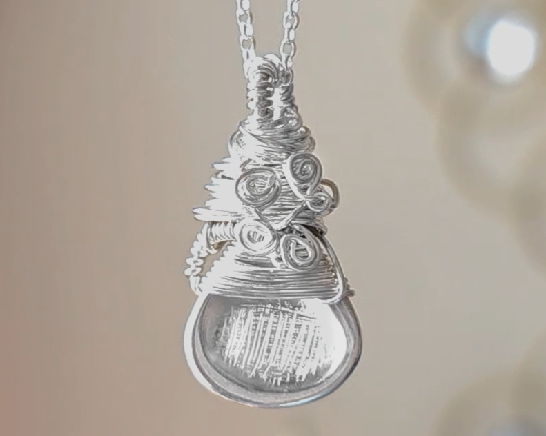 Sterling Silver Sculptural and Wire Wrapped Pendant with coils and texture on a rolo style chain with beige blurred background 