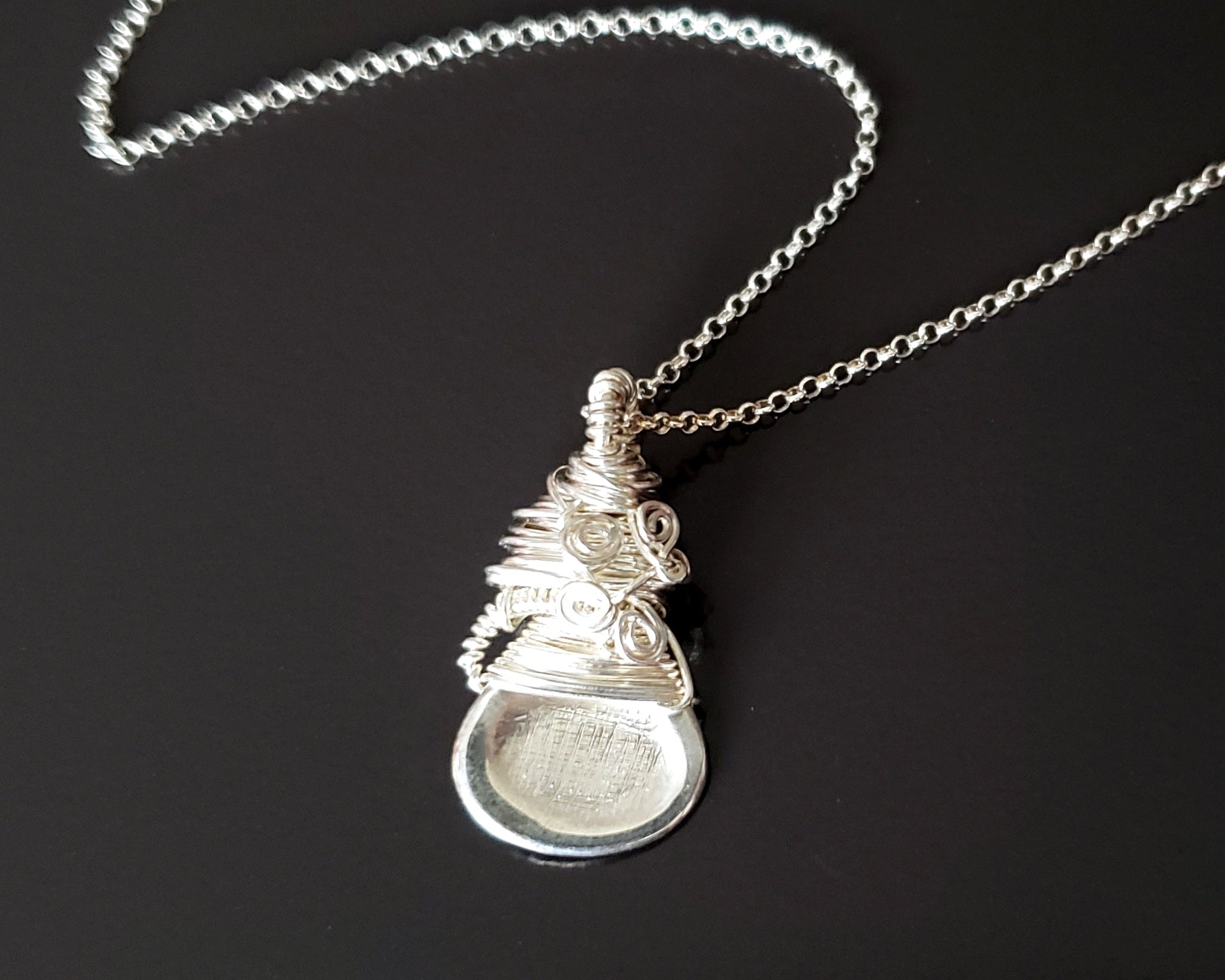Sterling Silver Sculptural and Wire Wrapped Pendant with coils and texture on a rolo style chain on black background 