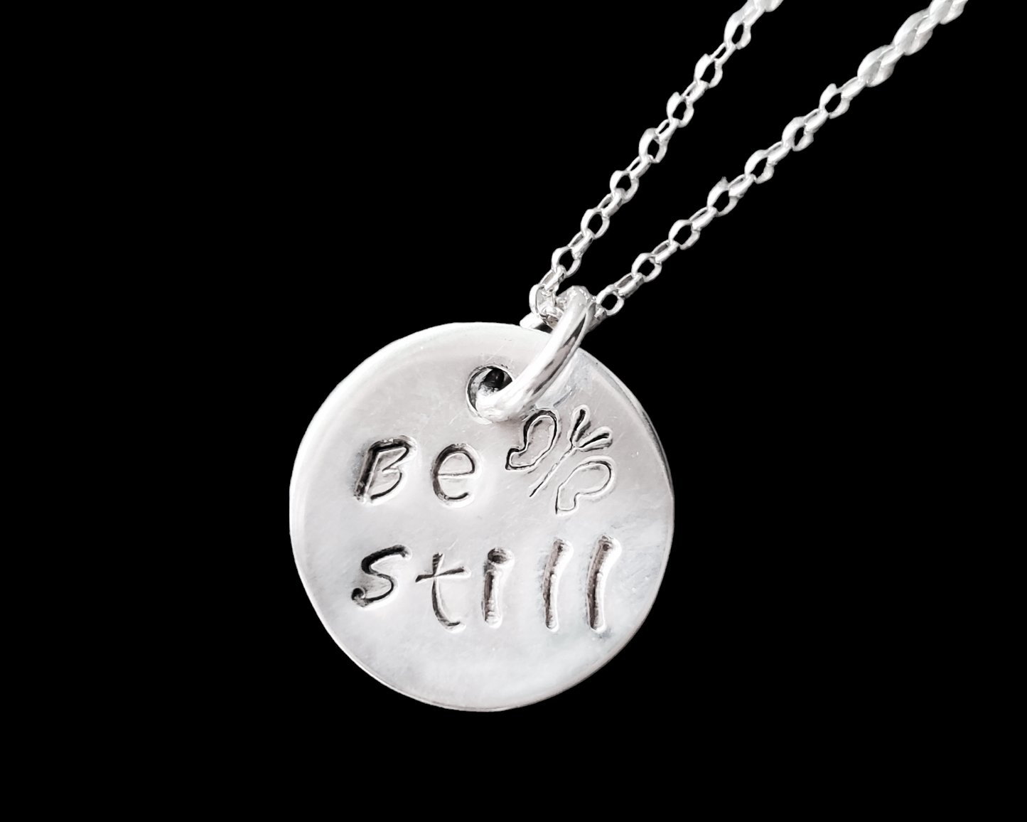 Sterling Silver Pendant that says Be Still and has a Butterfly, the Pendant is round and dangle on a rolo style chain.