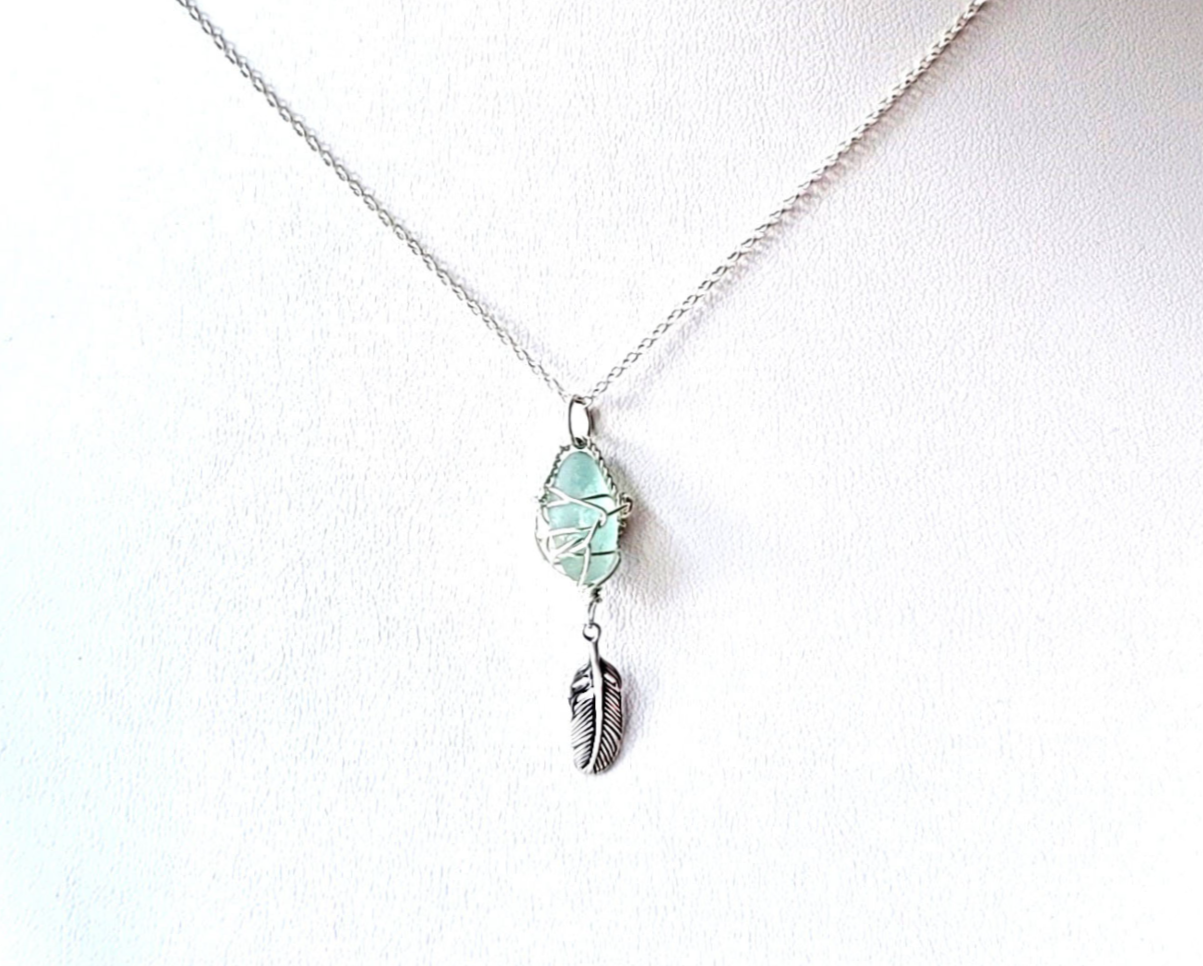 Sterling Silver, Aqua blue Beach Glass (Freshwater Sea Glass) Pendant, Wire Wrapped design with dangling Feather. The pendant dangles in rolo link chain.  