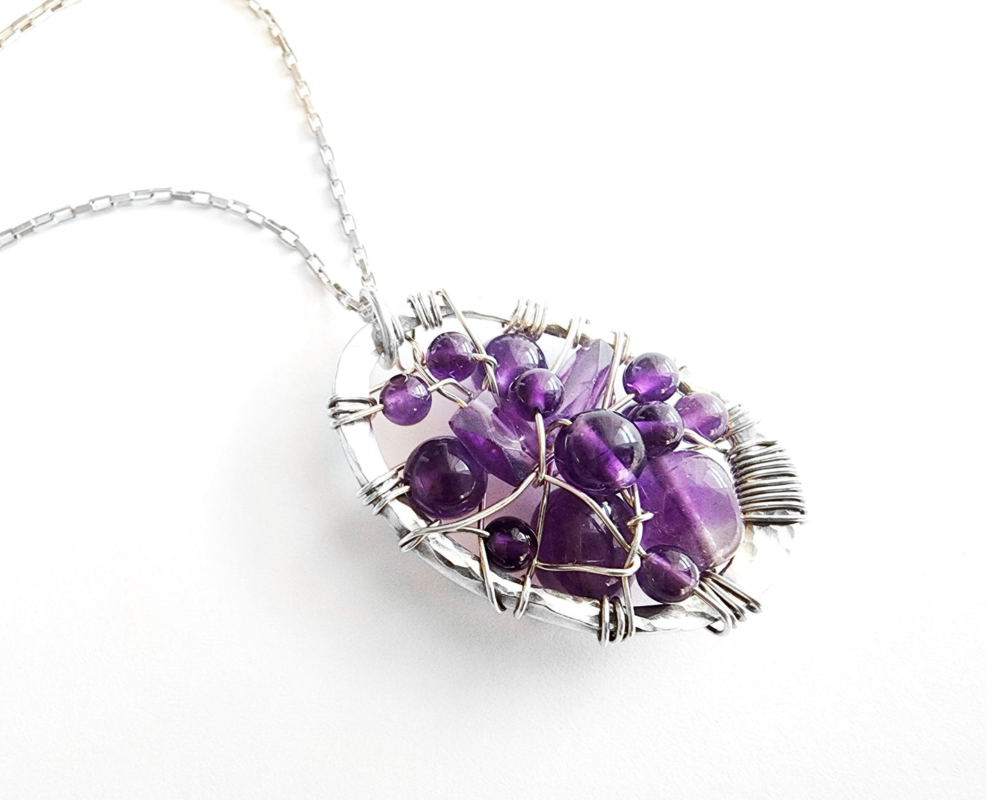 Oval shaped Sterling Silver Amethyst pendant woven with purple gemstones and Sterling Silver wire, pendant on chain.