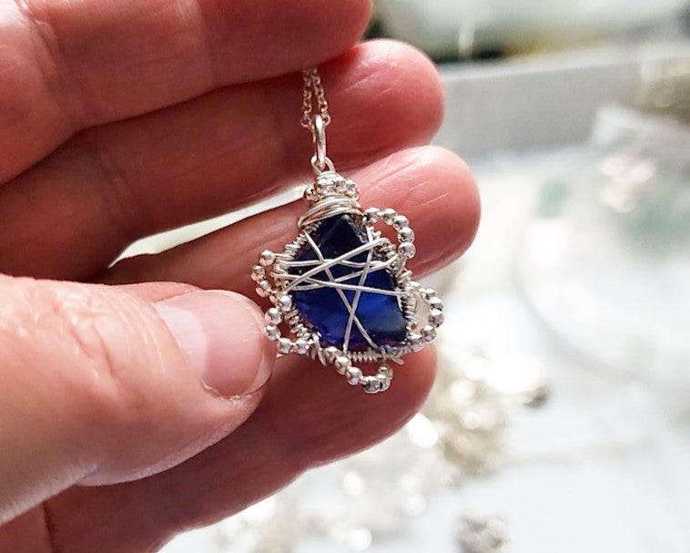 Sapphire Blue Beach Glass Flower Pendant- Freshwater Sea Glass
, Sterling Sivler Wire and tiny faceted Sterling silver beads to create a flower like design. Pendant dangles on Sterling Silver rolo chain. 
