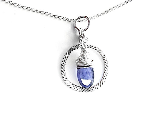 Handmade sterling silver pendant with Decorative Ring and wire wrapped oval shaped faceted purple Iolite gemstone dangling in the centre with round bail on chain with white background
