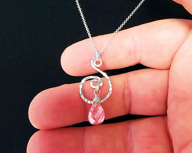 Celtic inspired Sterling Silver pendant with a delicate, lively hand forged design, a brilliant pink Cubic Zirconia dangle on Rolo chain on hand