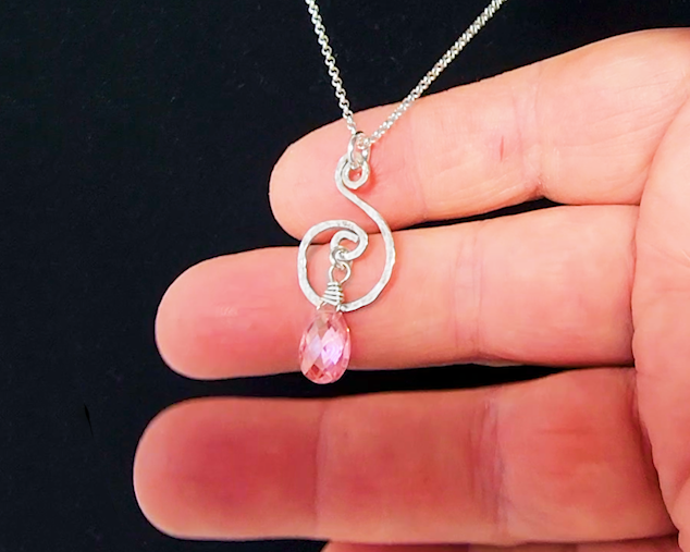 Celtic inspired Sterling Silver pendant with a delicate, lively hand forged design, a brilliant pink Cubic Zirconia dangle on Rolo chain on hand