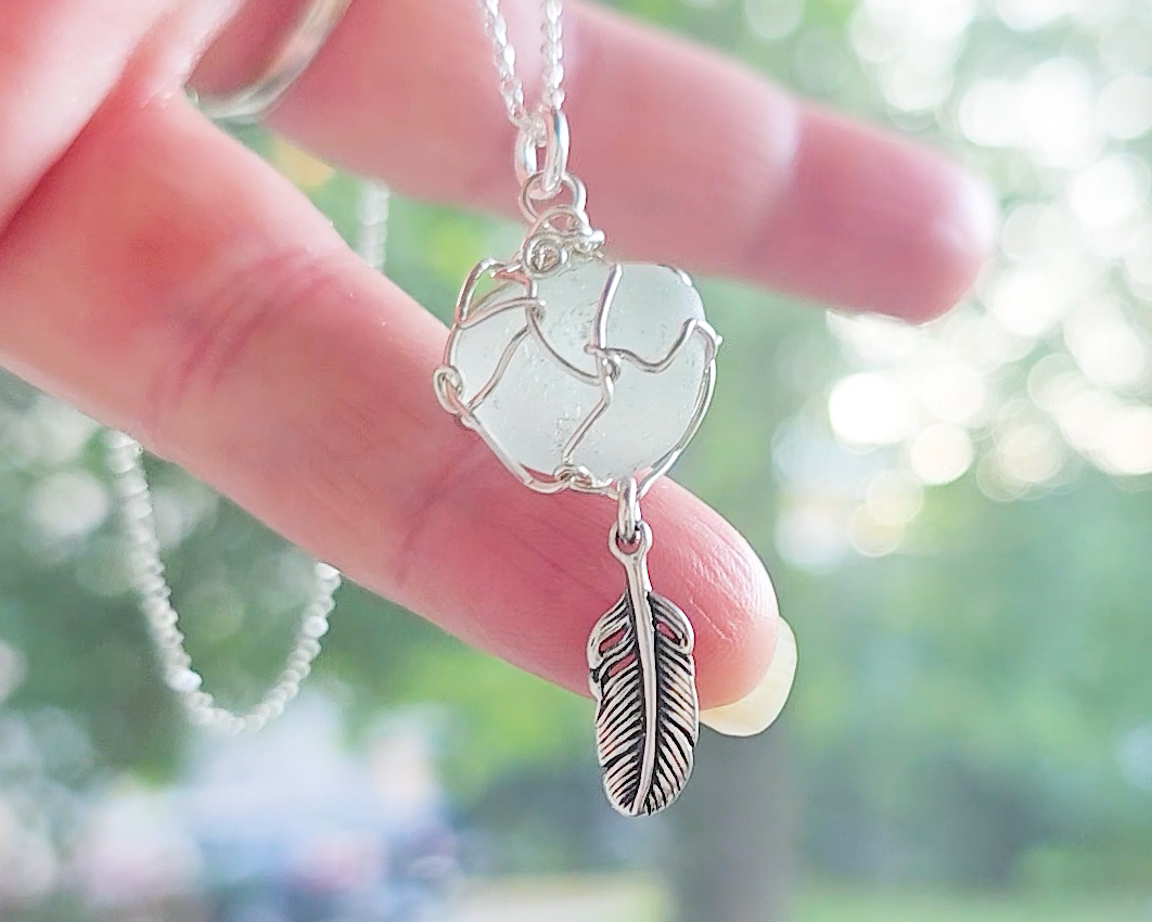 Silver Pendant with Aqua Blue Sea Glass and dangling Silver Feather on Silver Rolo chain displayed in hand