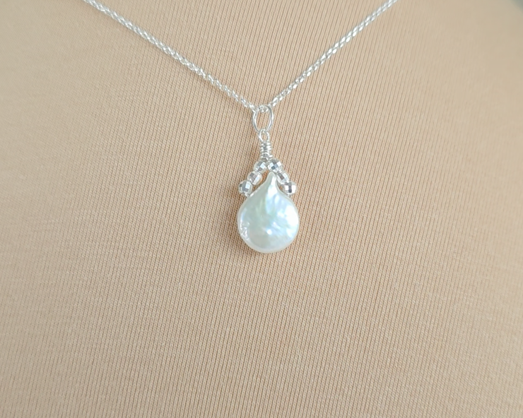 Handmade Sterling Silver Pearl Pendant with a large rounder drop shape white freshwater Cultured Pearl with sparkly silver beads wire wrapped to a round bail on silver chain with beige background 