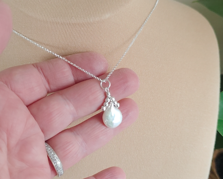 Handmade Sterling Silver Pearl Pendant with a large rounder drop shape white freshwater Cultured Pearl with sparkly silver beads wire wrapped to a round bail on silver chain in hand 