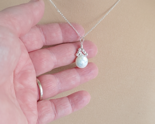 Handmade Sterling Silver Pearl Pendant with a large rounder drop shape white freshwater Cultured Pearl with sparkly silver beads wire wrapped to a round bail on silver chain in hand 