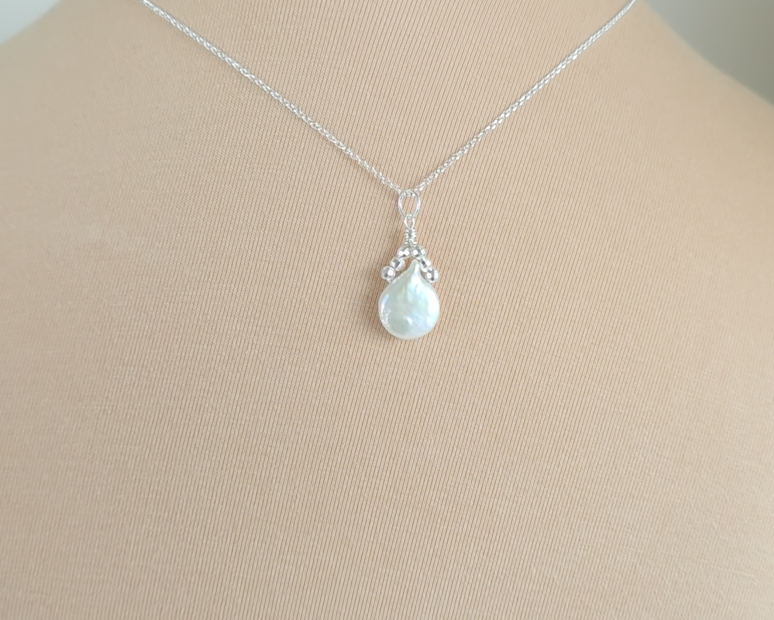 Handmade Sterling Silver Pearl Pendant with a large rounder drop shape white freshwater Cultured Pearl with sparkly silver beads wire wrapped to a round bail on silver chain with beige background 